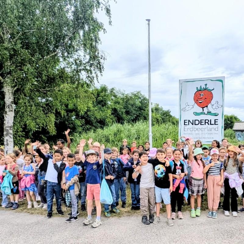 Schüler:innen vor einem Schild auf dem Enderle Erdbeerland steht